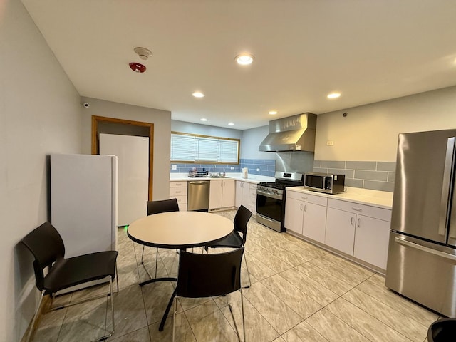 14401 Pulaski Rd, Midlothian, IL 60445 - kitchen featuring appliances with stainless steel finishes, wall chimney range hood, light countertops, tasteful backsplash, and white cabinetry