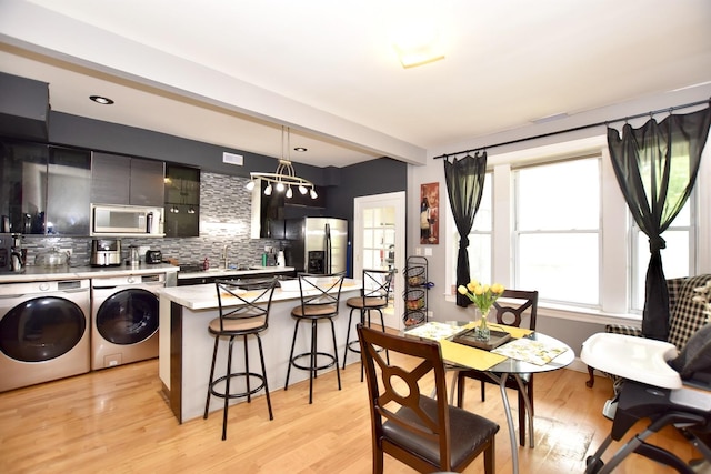 4220 S Champlain Ave Unit 2N, Chicago, IL 60653 - dining room featuring washer and clothes dryer, light wood finished floors, beam ceiling, and a chandelier