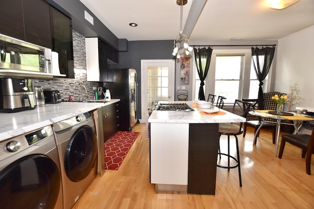 4220 S Champlain Ave Unit 2N, Chicago, IL 60653 - kitchen featuring a breakfast bar area, washing machine and dryer, light wood-type flooring, backsplash, and a center island