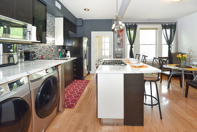 4220 S Champlain Ave Unit 2N, Chicago, IL 60653 - kitchen featuring washing machine and dryer, stainless steel fridge with ice dispenser, a kitchen breakfast bar, a kitchen island, and plenty of natural light
