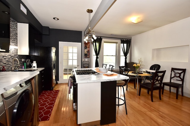 4220 S Champlain Ave Unit 2N, Chicago, IL 60653 - kitchen with washer / dryer, a breakfast bar area, light countertops, backsplash, and light wood-style flooring