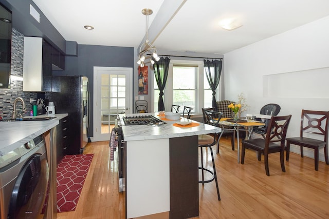 4220 S Champlain Ave Unit 2N, Chicago, IL 60653 - kitchen with washer / clothes dryer, a kitchen bar, light wood-type flooring, tasteful backsplash, and a kitchen island