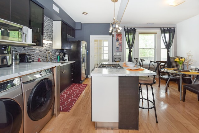 4220 S Champlain Ave Unit 2N, Chicago, IL 60653 - kitchen featuring stainless steel appliances, separate washer and dryer, a kitchen bar, tasteful backsplash, and a center island