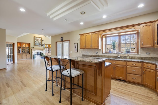 3412 Sunnyside Ct, Naperville, IL 60564 - kitchen with brown cabinets, a breakfast bar area, light wood-style flooring, vaulted ceiling, and recessed lighting