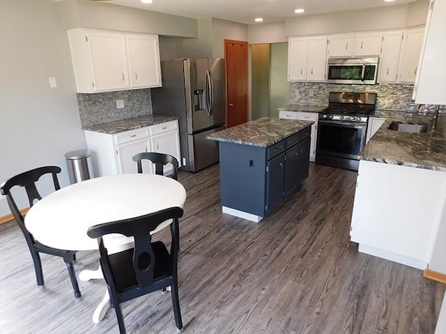 1637 Old Field Ct, Rockton, IL 61072 - kitchen with appliances with stainless steel finishes, a kitchen island, white cabinets, decorative backsplash, and dark wood-style floors