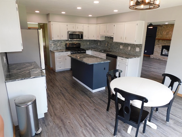 1637 Old Field Ct, Rockton, IL 61072 - kitchen with stainless steel appliances, a kitchen island, white cabinetry, dark stone countertops, and dark wood-style flooring