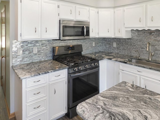 1637 Old Field Ct, Rockton, IL 61072 - kitchen with stainless steel appliances, white cabinetry, dark stone countertops, and tasteful backsplash