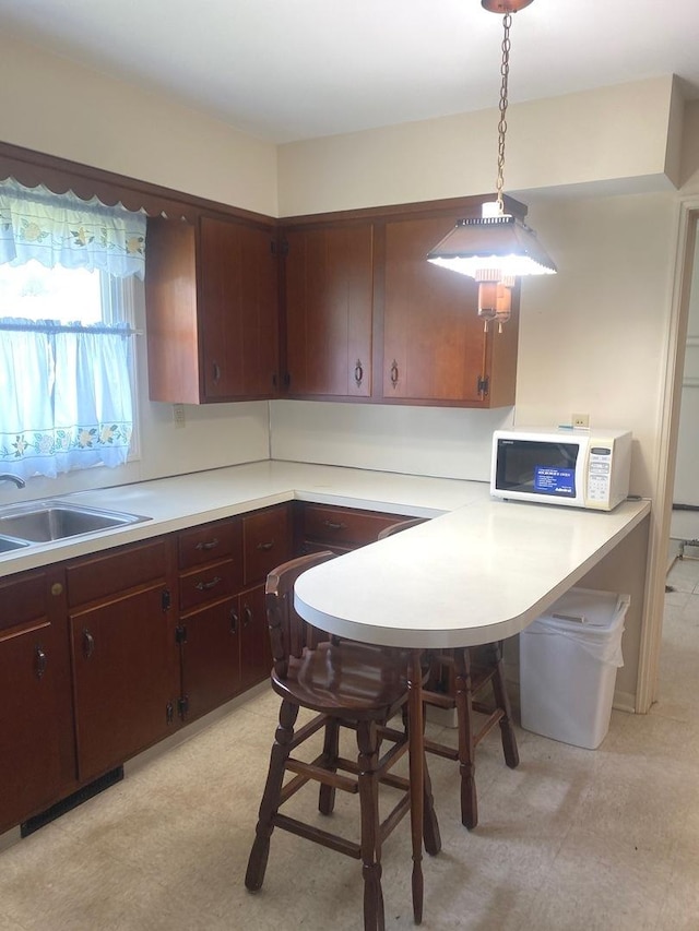 1415 Lakewood Dr, Mendota, IL 61342 - kitchen featuring white microwave, light flooring, light countertops, and hanging light fixtures
