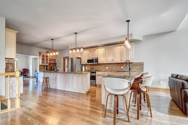 1383 Gordon Ln, Lemont, IL 60439 - kitchen featuring stainless steel appliances, a breakfast bar area, decorative backsplash, light wood-style flooring, and glass insert cabinets