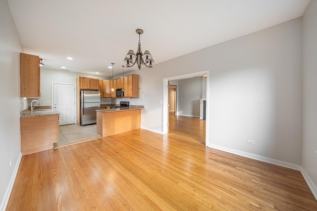 6829 N Lakewood Ave Unit 3, Chicago, IL 60626 - kitchen with freestanding refrigerator, a chandelier, brown cabinets, stove, and a peninsula