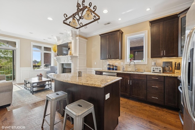 3252 N California Ave Unit 2, Chicago, IL 60618 - kitchen with a kitchen island, crown molding, a kitchen breakfast bar, dark brown cabinetry, and open floor plan