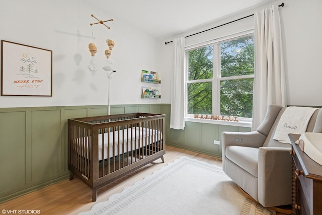 1048 W Lill Ave Unit 2, Chicago, IL 60614 - bedroom with wood finished floors, a crib, a decorative wall, and wainscoting