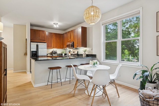 1048 W Lill Ave Unit 2, Chicago, IL 60614 - kitchen with appliances with stainless steel finishes, light wood finished floors, a peninsula, dark countertops, and a breakfast bar area