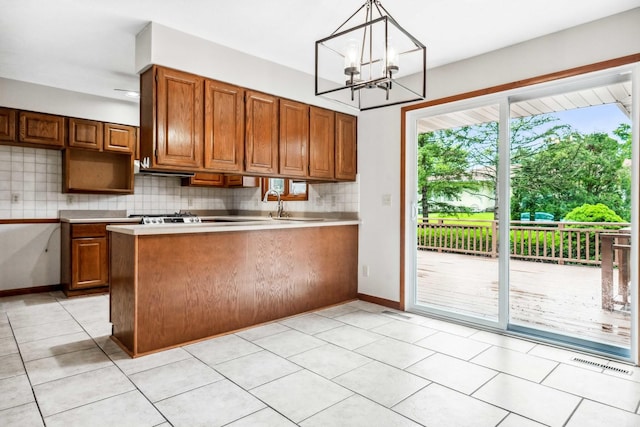 207 Hammitt Dr, Normal, IL 61761 - kitchen featuring a peninsula, brown cabinets, decorative backsplash, a chandelier, and light countertops