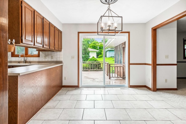 207 Hammitt Dr, Normal, IL 61761 - kitchen featuring light countertops, brown cabinets, a chandelier, hanging light fixtures, and backsplash