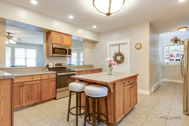 20760 N Florence Ave, Lincolnshire, IL 60069 - kitchen with stainless steel appliances, light tile patterned floors, light countertops, a center island, and recessed lighting