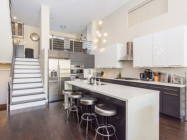 2036 W Huron St, Chicago, IL 60612 - kitchen with stainless steel appliances, wall chimney exhaust hood, dark wood-style floors, a breakfast bar area, and modern cabinets