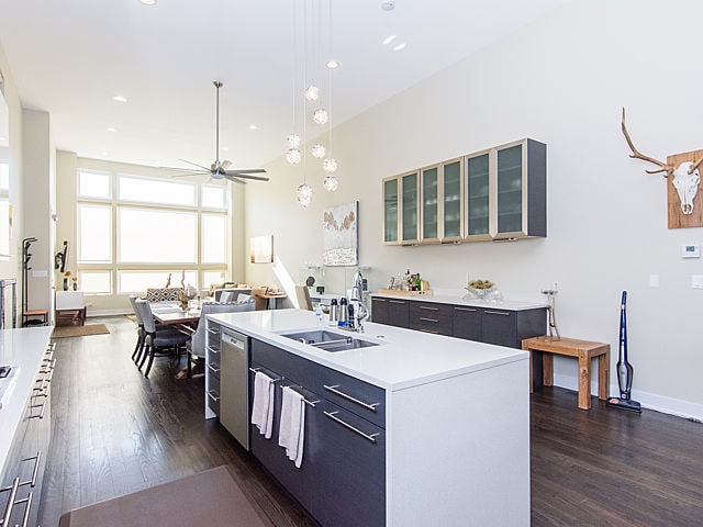 2036 W Huron St, Chicago, IL 60612 - kitchen with dark wood finished floors, light countertops, an island with sink, glass insert cabinets, and ceiling fan