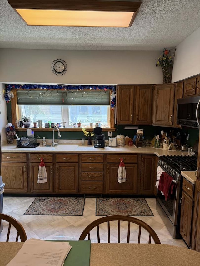 kitchen featuring stainless steel appliances, light countertops, a textured ceiling, and light floors