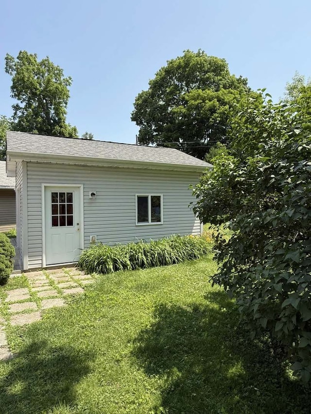 rear view of house with a lawn and roof with shingles
