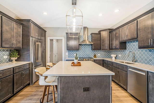 17035 Clover Dr, Orland Park, IL 60467 - kitchen with wall chimney exhaust hood, appliances with stainless steel finishes, dark brown cabinetry, a kitchen breakfast bar, and light wood finished floors