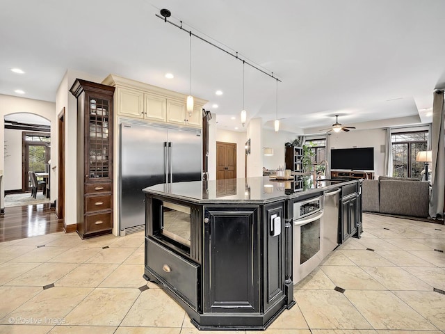 22 Yorkshire Woods, Oak Brook, IL 60523 - kitchen with dark cabinetry, built in appliances, a ceiling fan, arched walkways, and open floor plan