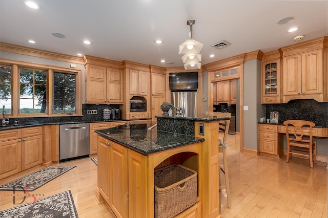524 E Van Buren St, Ottawa, IL 61350 - kitchen featuring appliances with stainless steel finishes, a kitchen island, glass insert cabinets, backsplash, and light wood-style flooring