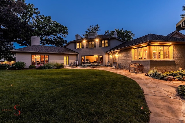 524 E Van Buren St, Ottawa, IL 61350 - rear view of house with brick siding, a patio, a chimney, and a lawn
