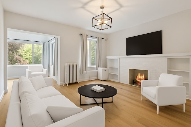 918 W Sunnyside Ave Unit 1B, Chicago, IL 60640 - living room featuring radiator, light wood finished floors, a chandelier, and a brick fireplace