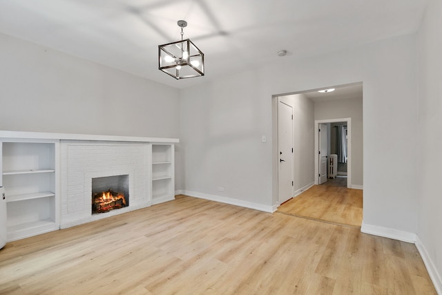 918 W Sunnyside Ave Unit 1B, Chicago, IL 60640 - unfurnished living room featuring wood finished floors, a brick fireplace, a chandelier, and built in shelves