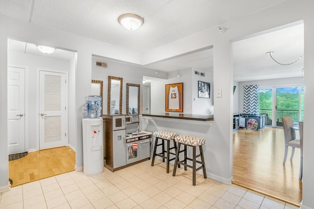 6807 N Milwaukee Ave Unit 411, Niles, IL 60714 - kitchen with wood finished floors, a breakfast bar, and a textured ceiling