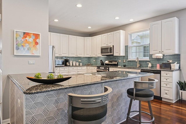 1845 Avon Dr, Hoffman Estates, IL 60192 - kitchen featuring appliances with stainless steel finishes, a breakfast bar, dark wood-type flooring, backsplash, and white cabinetry