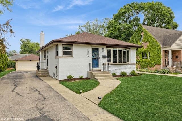 127 Elm St, Glenview, IL 60025 - bungalow-style home with a detached garage, a chimney, an outbuilding, a front yard, and roof with shingles