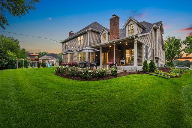51 Mitchell Cir, Wheaton, IL 60189 - back of property at dusk featuring a chimney, a yard, and a playground