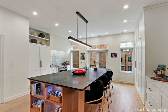 358 W Huron St Unit B, Chicago, IL 60654 - kitchen with open shelves, light wood-type flooring, white cabinets, an island with sink, and recessed lighting