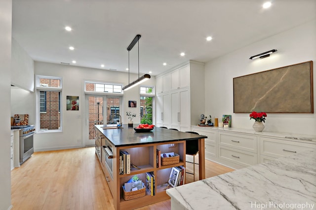 358 W Huron St Unit B, Chicago, IL 60654 - kitchen featuring stainless steel range, light wood-style floors, white cabinets, light stone countertops, and recessed lighting