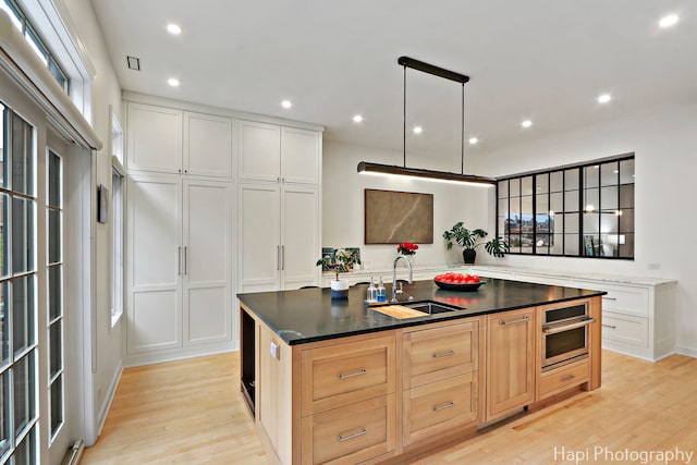 358 W Huron St Unit B, Chicago, IL 60654 - kitchen featuring light wood-style flooring, an island with sink, stainless steel oven, recessed lighting, and white cabinets