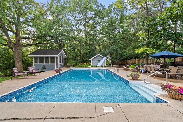 13302 Archer Ave, Lemont, IL 60439 - view of swimming pool featuring a sunroom, a water slide, a patio area, view of wooded area, and a storage unit