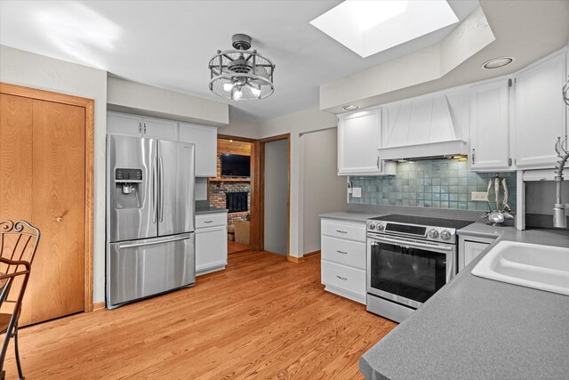 13302 Archer Ave, Lemont, IL 60439 - kitchen featuring appliances with stainless steel finishes, premium range hood, a skylight, tasteful backsplash, and white cabinetry