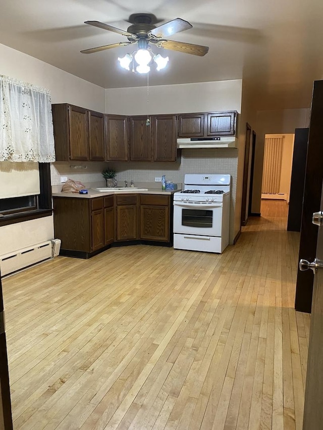 5015 S Talman Ave, Chicago, IL 60632 - kitchen with white range with gas stovetop, a baseboard radiator, under cabinet range hood, a ceiling fan, and light wood-style floors