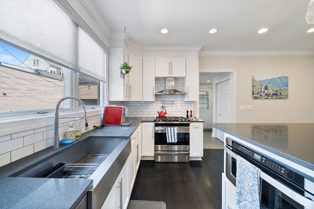 2012 W Charleston St, Chicago, IL 60647 - kitchen featuring stainless steel appliances, wall chimney exhaust hood, dark countertops, white cabinets, and ornamental molding