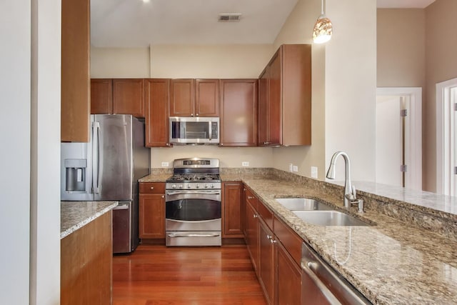 520 S State St Unit 1726, Chicago, IL 60605 - kitchen with appliances with stainless steel finishes, brown cabinetry, dark wood-type flooring, light stone counters, and decorative light fixtures