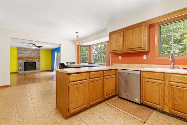 7204 Warblers Way, Roscoe, IL 61073 - kitchen with stainless steel dishwasher, light countertops, a peninsula, a brick fireplace, and light tile patterned flooring