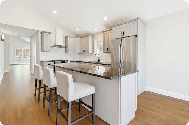 1544 N Wolf Rd, Berkeley, IL 60163 - kitchen featuring freestanding refrigerator, wall chimney range hood, lofted ceiling, tasteful backsplash, and a kitchen breakfast bar
