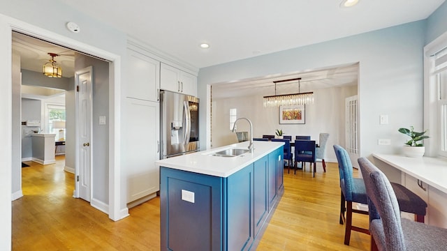 1712 Dobson St, Evanston, IL 60202 - kitchen with blue cabinetry, light wood finished floors, white cabinets, light countertops, and a chandelier