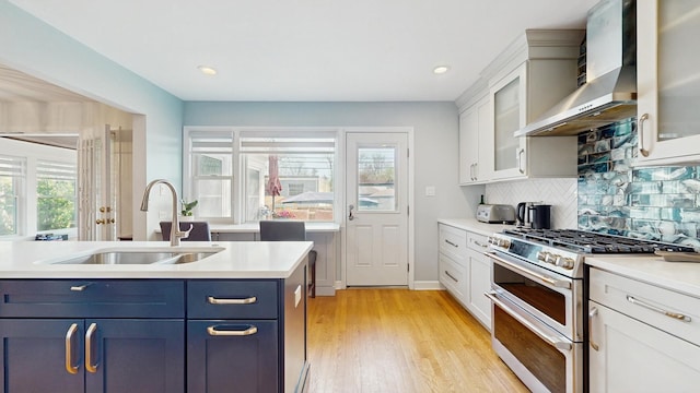 1712 Dobson St, Evanston, IL 60202 - kitchen with wall chimney exhaust hood, range with two ovens, light countertops, blue cabinets, and light wood-style floors