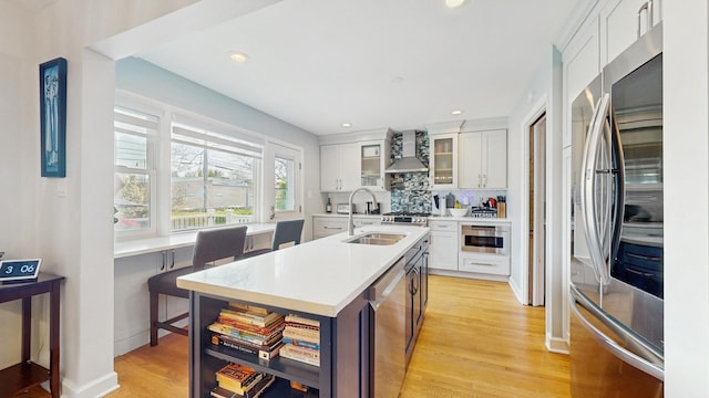 1712 Dobson St, Evanston, IL 60202 - kitchen with stainless steel appliances, wall chimney exhaust hood, light countertops, a kitchen island with sink, and white cabinets