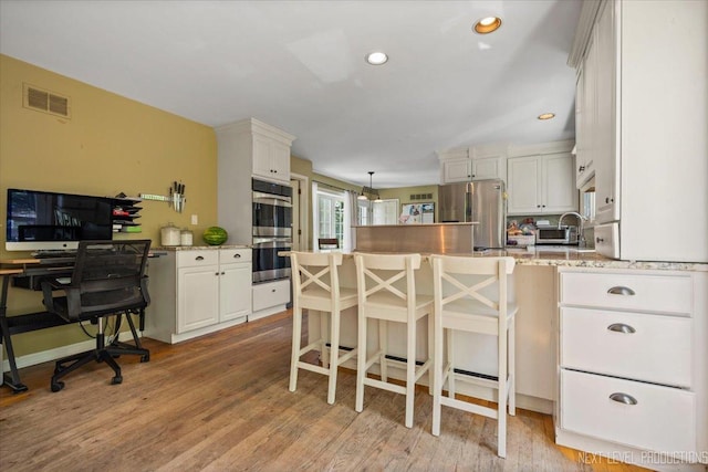 932 S Batavia Ave, Geneva, IL 60134 - kitchen with appliances with stainless steel finishes, a peninsula, white cabinets, light stone counters, and light wood-style flooring
