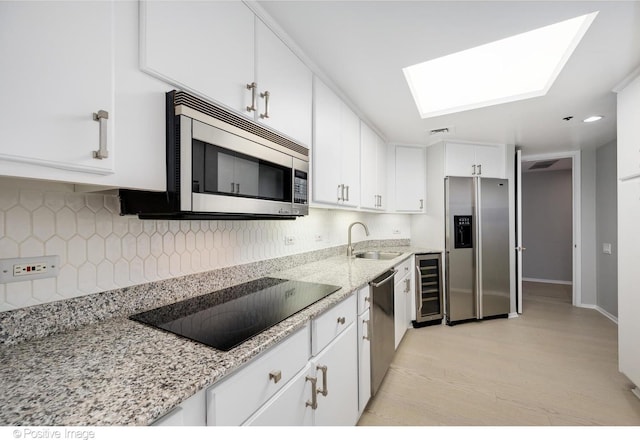 950 N Michigan Ave Unit 2901, Chicago, IL 60611 - kitchen featuring appliances with stainless steel finishes, beverage cooler, white cabinetry, backsplash, and a skylight