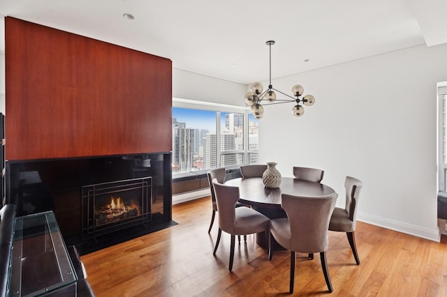 800 N Michigan Ave Unit 3103, Chicago, IL 60611 - dining room featuring light wood-style flooring, a chandelier, a fireplace with flush hearth, and a view of city